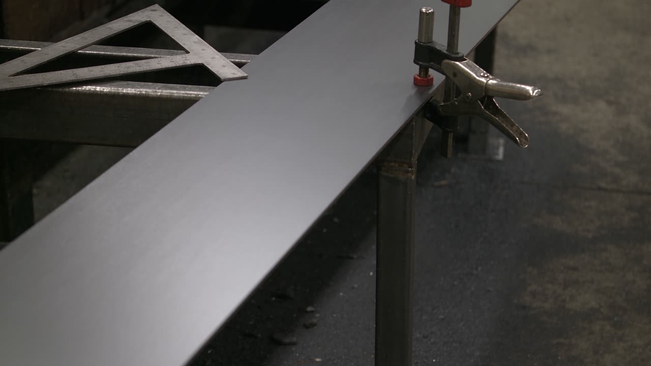 Steel plate clamped square on a fabrication bench with sparks behind it